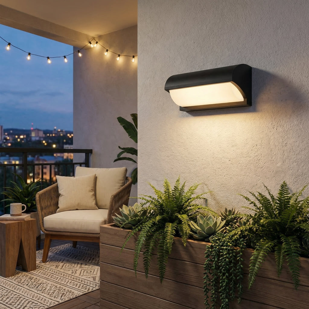 Outdoor wall light fixture on a wall with plants and a patio in the background