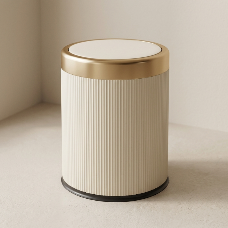 Beige cylindrical trash can with a gold lid on a beige background