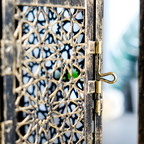 Decorative metal gate with intricate patterns and a blurred background