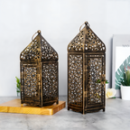 Two ornate brass lanterns on a light surface with a white background
