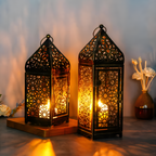Two ornate lanterns with intricate designs, emitting a warm glow, on a soft focus background.