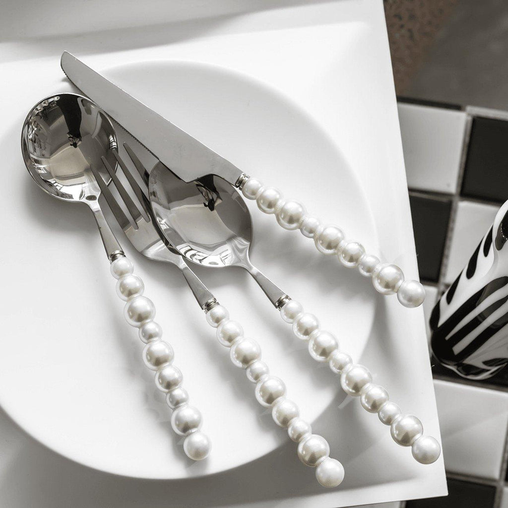 Silver cutlery set with pearl handles on a white plate
