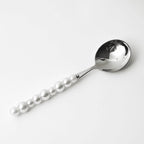Spoon with pearl-like beads on a white background