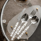 Silver cutlery set with pearls on a textured surface