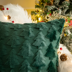 Green textured pillow in front of a decorated Christmas tree with lights and ornaments.