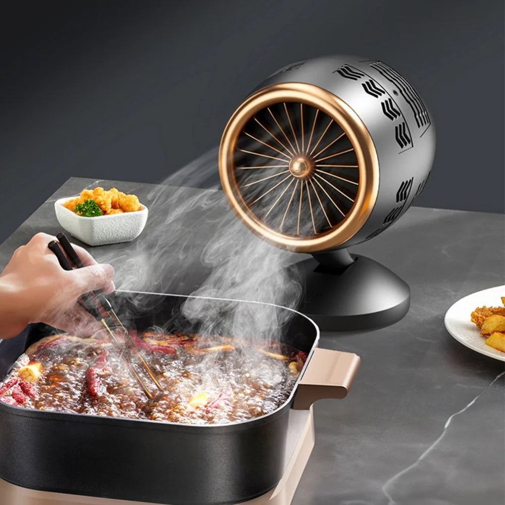 Person cooking food on a grill with a small fan blowing air over it, on a dark surface.
