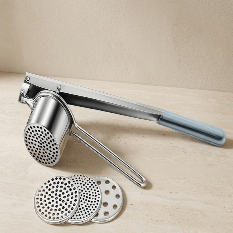 Metallic kitchen tool with interchangeable parts on a beige surface