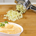 Mashed cauliflower on a wooden cutting board with a hand masher, next to a bowl of mashed cauliflower.