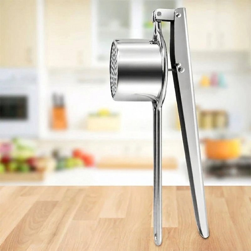 Metallic kitchen masher on a wooden surface with a blurred kitchen background