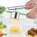 Stainless steel potato masher being used to mash potatoes with a bowl and plate of food in the background.