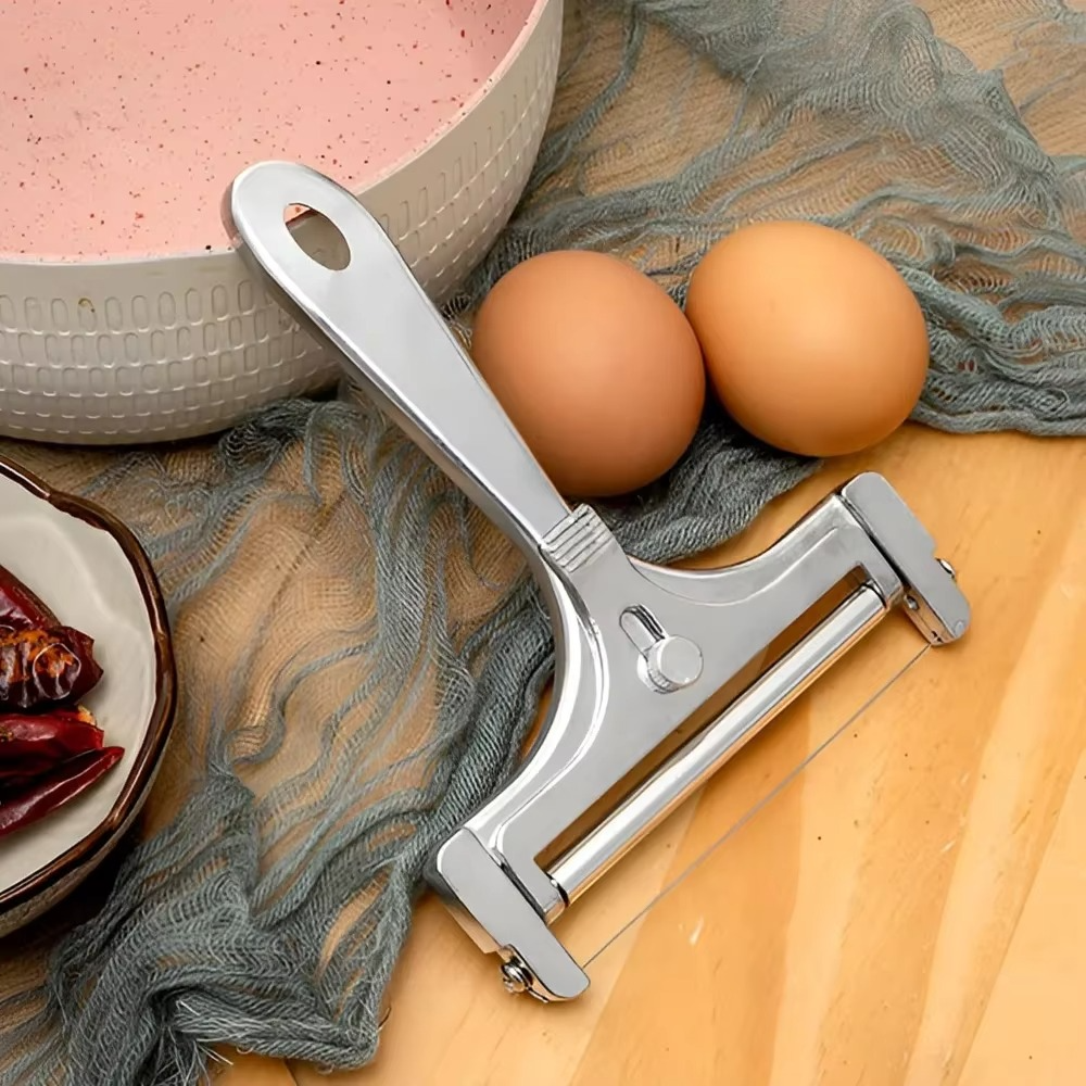 Metal peeler on a wooden surface with eggs and a bowl in the background