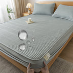 Gray mattress cover on a bed with a person holding it, in a bedroom setting.