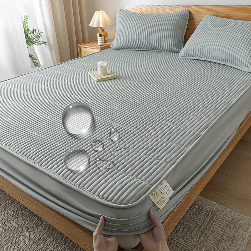 Gray mattress cover on a bed with a person holding it, in a bedroom setting.