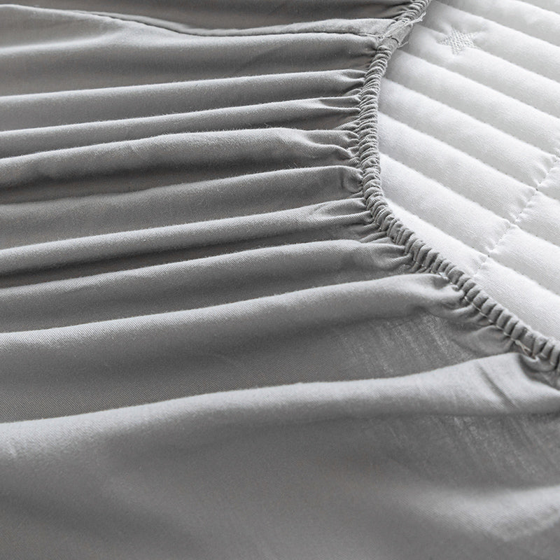 Close-up of a fitted sheet on a bed with a textured surface.