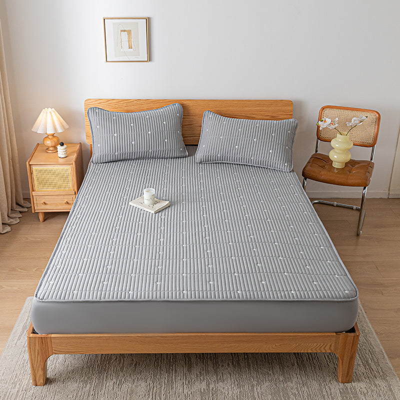 Bed with gray mattress cover and pillows in a bedroom setting.
