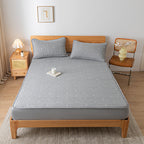Bed with gray mattress cover and pillows in a bedroom setting.