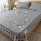 Gray textured mattress cover being held on a bed in a bedroom setting.