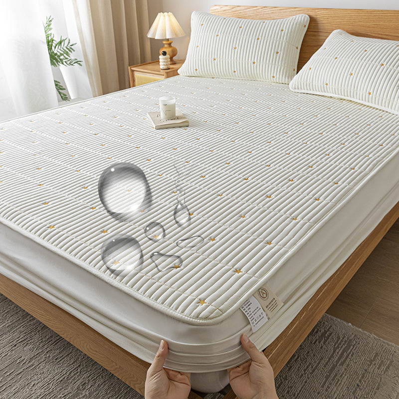 Mattress cover on a bed with a hand holding it, in a bedroom setting.
