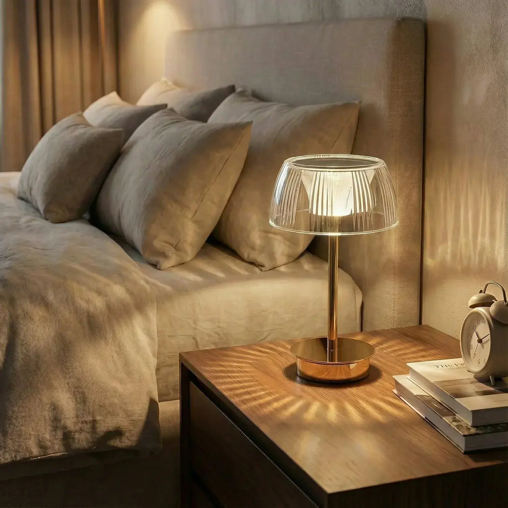 Lamp on a bedside table next to a bed with pillows in a cozy bedroom setting