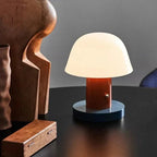 Small table lamp with a wooden base on a dark surface against a gray wall