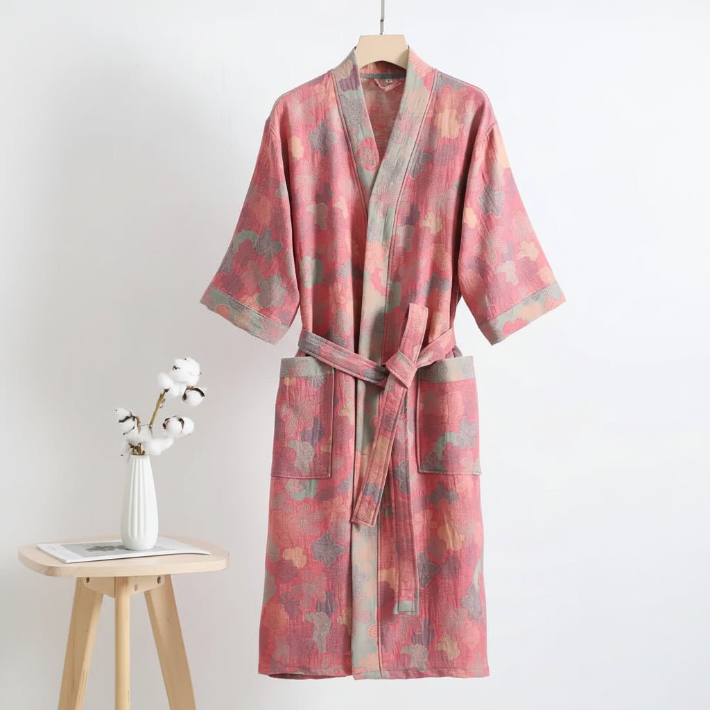 Pink floral patterned robe on a hanger against a white background