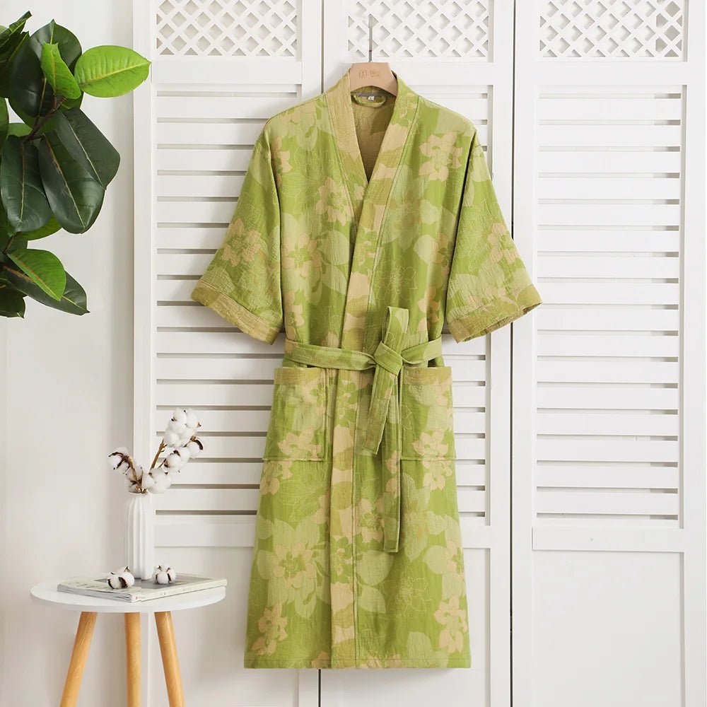 Green floral-patterned robe hanging on a white lattice door with a plant and small table in the background.