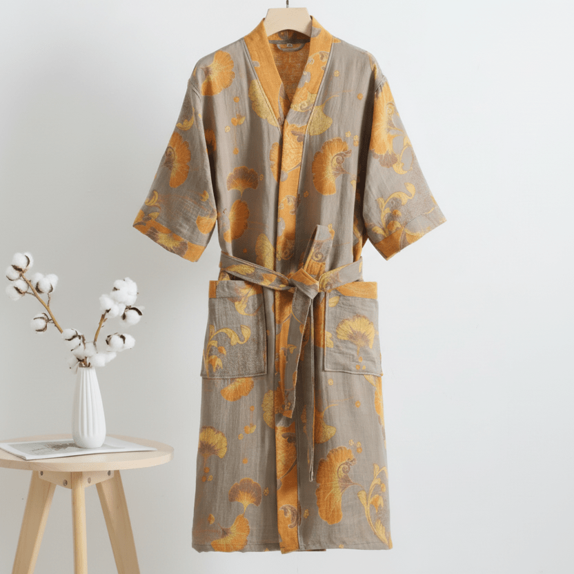 Gray and orange patterned robe on a hanger with a small wooden table and vase in the background.