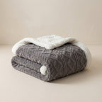 Folded gray and white textured blanket on a beige surface