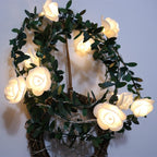 Decorative wreath with glowing white roses and green leaves on a plain background