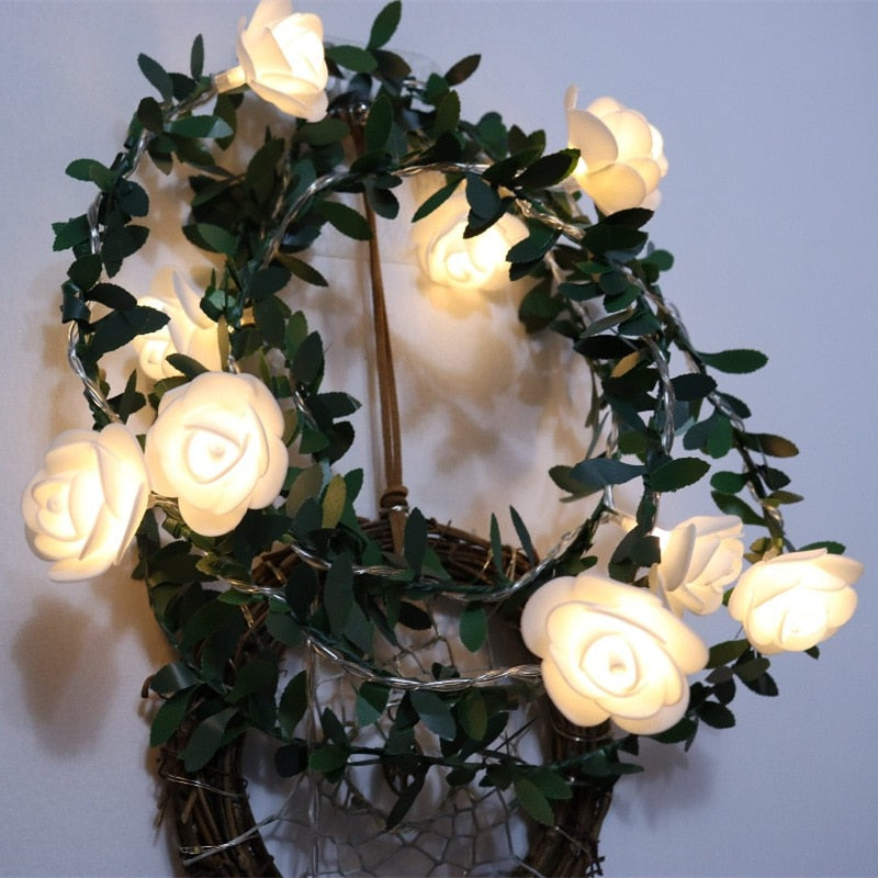 Decorative wreath with glowing white roses and green leaves on a plain background