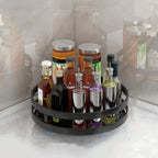 Black circular bottle organizer with various bottles on a white surface.