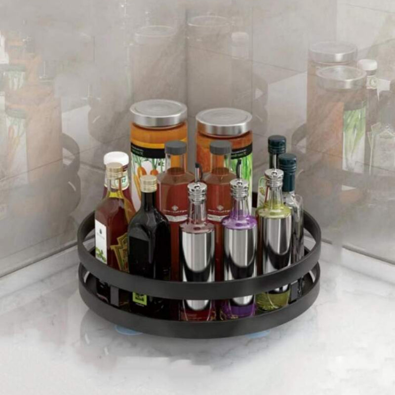 Black circular bottle organizer with various bottles on a white surface.