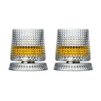 Two crystal glasses with textured design filled with a yellow liquid on a white background