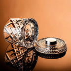 Decorative glass container with intricate design on a reflective surface against an orange background
