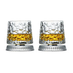 Two crystal glasses filled with a yellow liquid on a white background