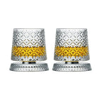Two crystal glasses with diamond pattern filled with a yellow liquid on a white background