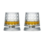 Two clear glass tumblers with textured design filled with a yellow liquid on a white background.