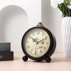 Decorative clock on a table with a vase of flowers in the background