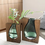 Two glass vases with wooden bases on a white surface.
