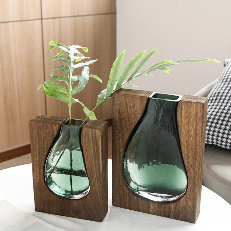Two glass vases with wooden bases on a white surface.