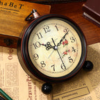 Vintage-style clock on a wooden surface with a book and paper in the background