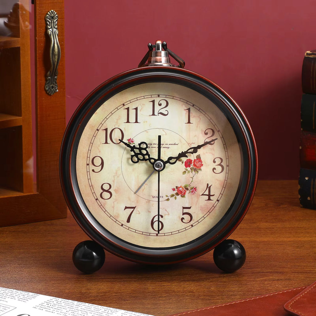Vintage-style alarm clock with floral design on a wooden surface