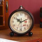 Vintage-style alarm clock with floral design on a wooden surface