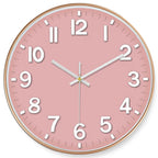 Round wall clock with a pink face and gold frame on a white background