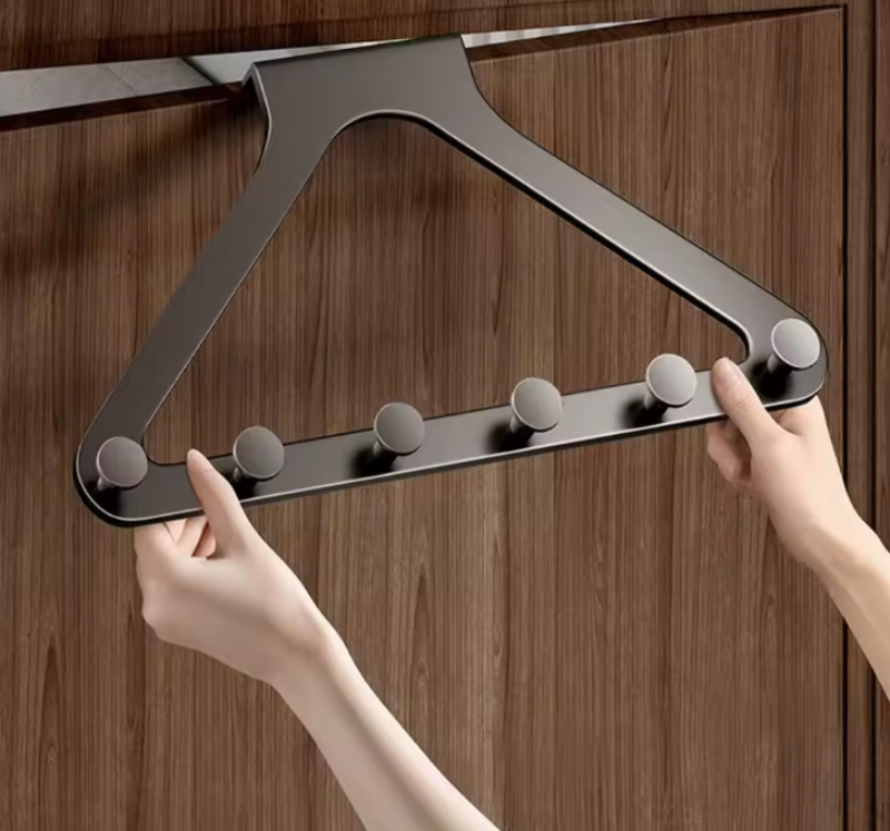 Metal hanger with multiple hooks held by a person against a wooden background