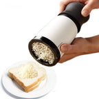 Hand holding a cheese grater over a slice of bread with grated cheese on a white background