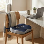 Blue and gray cushion on a wooden chair next to a desk with a laptop and mug.