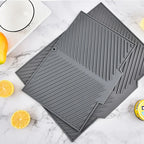 Three gray silicone mats on a marble surface with lemons and a bowl.