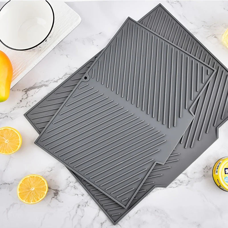 Three gray silicone mats on a marble surface with lemons and a bowl.