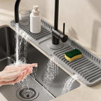 Person washing hands under running water in a kitchen sink with a沥水架 on the counter.